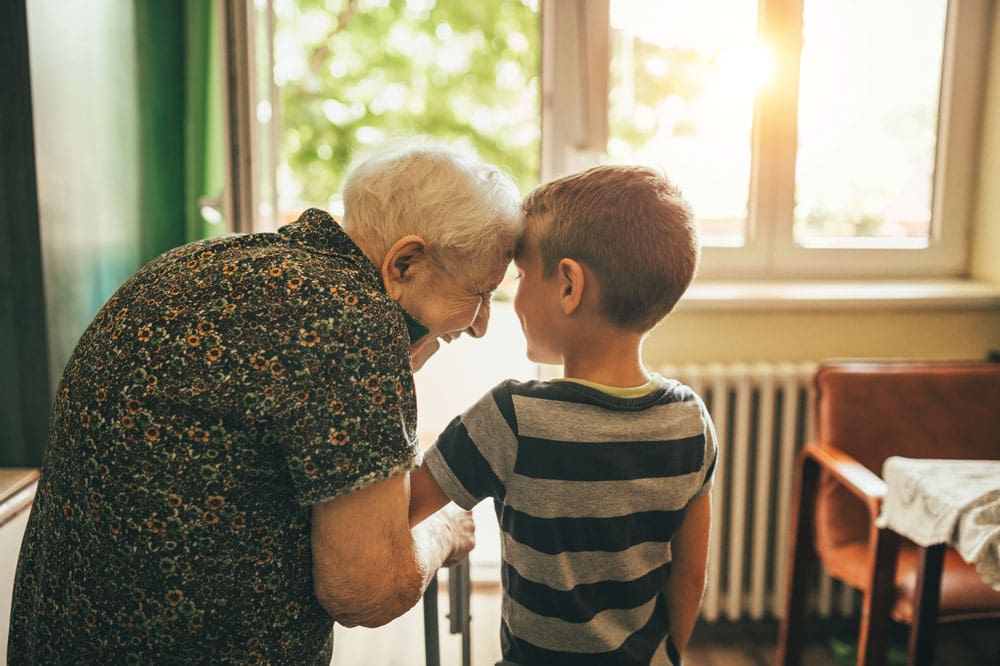 Charter Senior Living of Williamsburg resident standing in doorway with young grandson