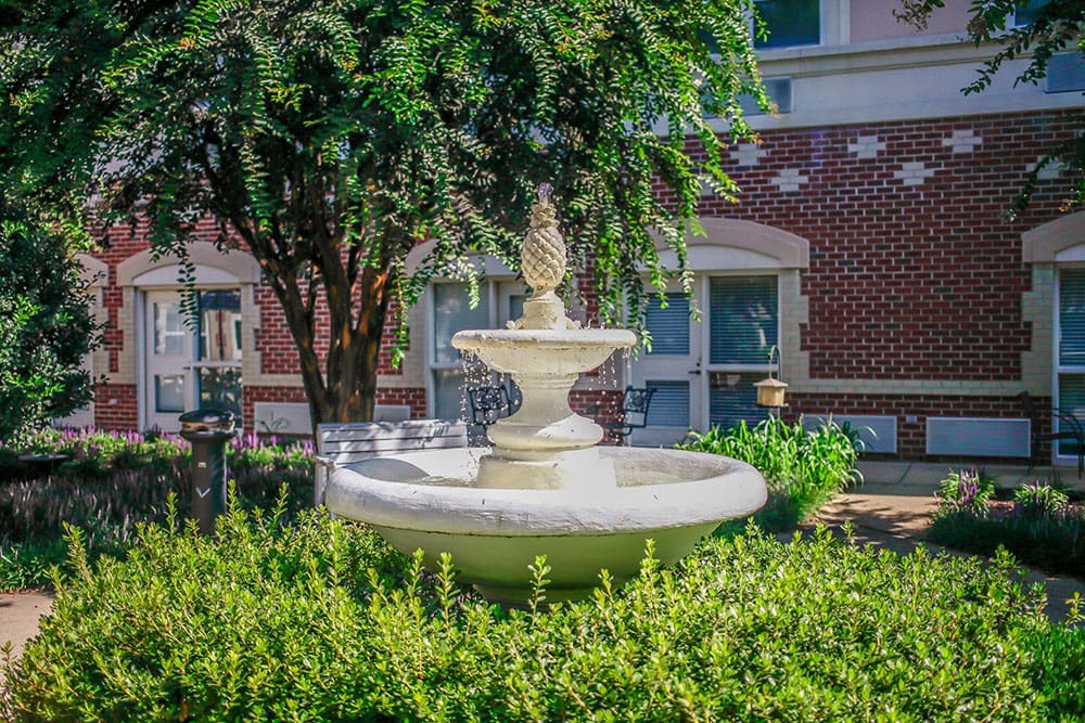 Decorative outdoor fountain surrounded by greenery at Charter Senior Living of Williamsburg, VA