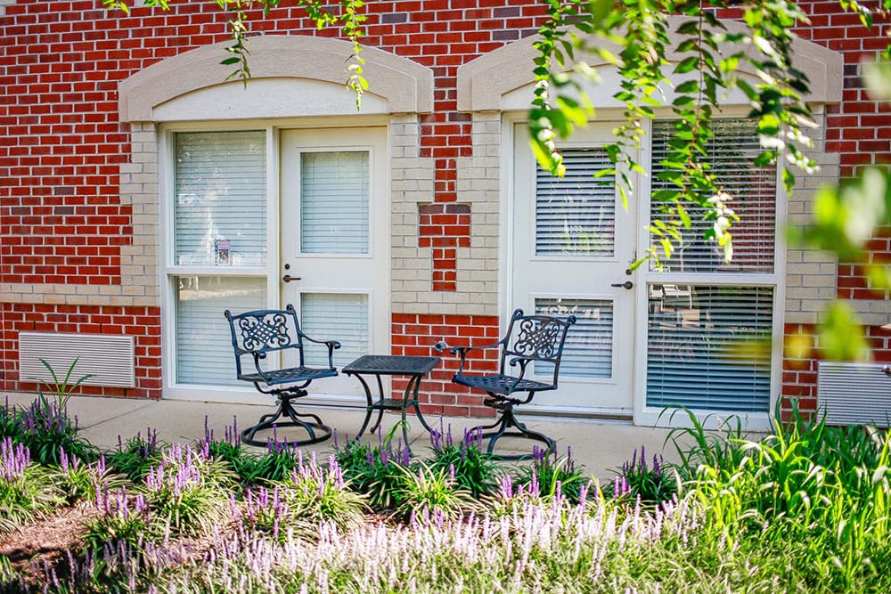 Charming resident patio space surrounded by flowers at Charter Senior Living of Williamsburg, VA
