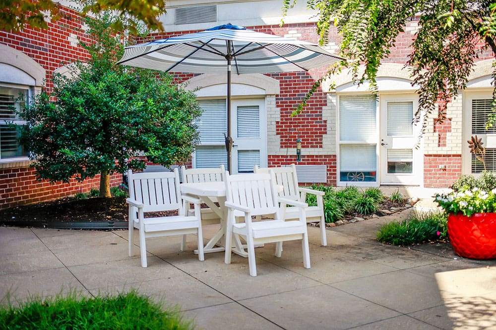 Patio table with umbrella for outdoor relaxation at Charter Senior Living in Williamsburg, Virginia